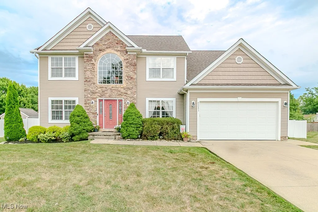 View of front of home with driveway, stone siding, and a garage
