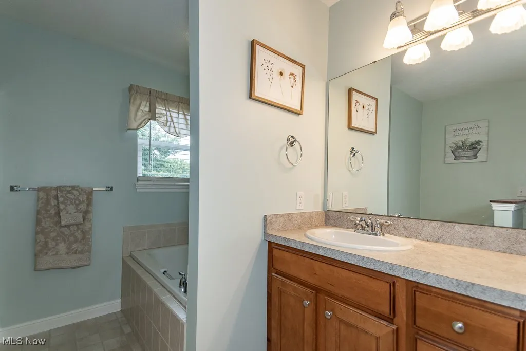 Bathroom featuring vanity, a bath, and light tile patterned floors