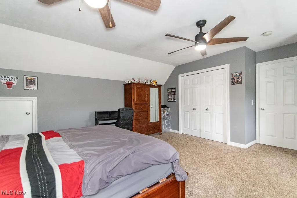 Carpeted bedroom featuring vaulted ceiling, a closet, and a ceiling fan