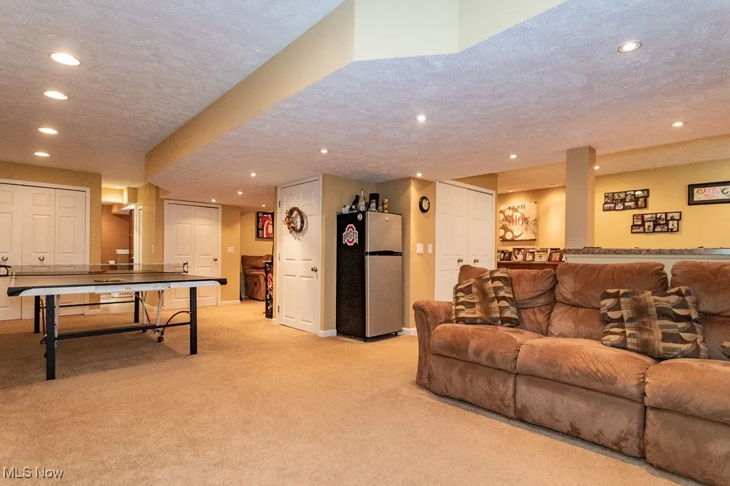 Living room with a textured ceiling, light carpet, and recessed lighting