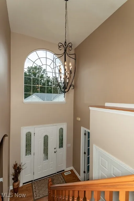 Entryway with wood finished floors, a chandelier, and a towering ceiling