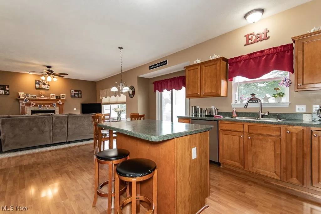 Kitchen featuring a kitchen bar, brown cabinetry, dark countertops, a center island, and light wood finished floors