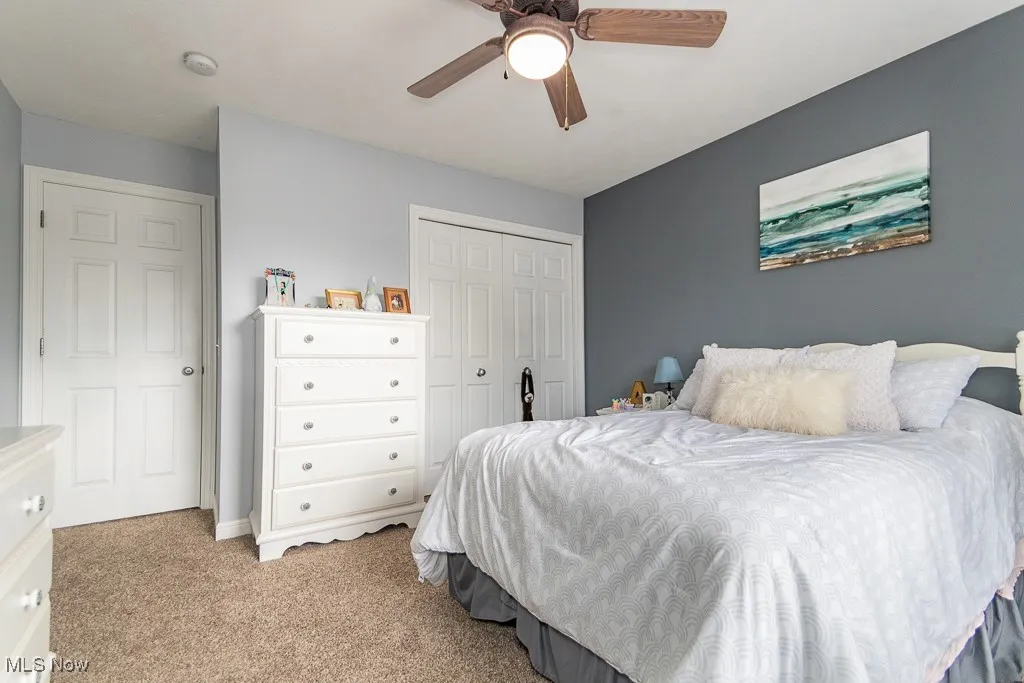 Bedroom featuring light carpet, a closet, and a ceiling fan