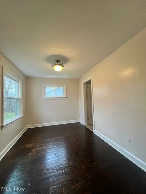 Unfurnished room featuring dark wood finished floors and baseboards