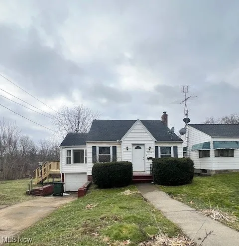 View of front of property featuring a front lawn, driveway, a chimney, and an attached garage