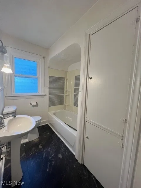 Bathroom with dark wood-type flooring and shower / tub combination