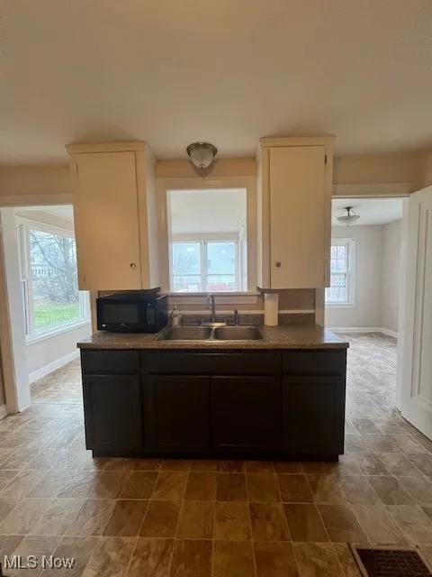 Kitchen with dark brown cabinetry, dark countertops, stone finish floors, and ceiling fan