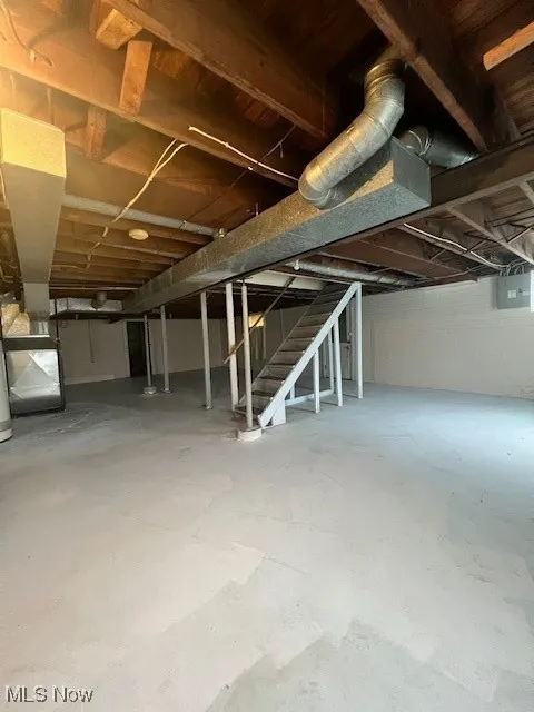 Unfinished basement featuring stairway and heating unit