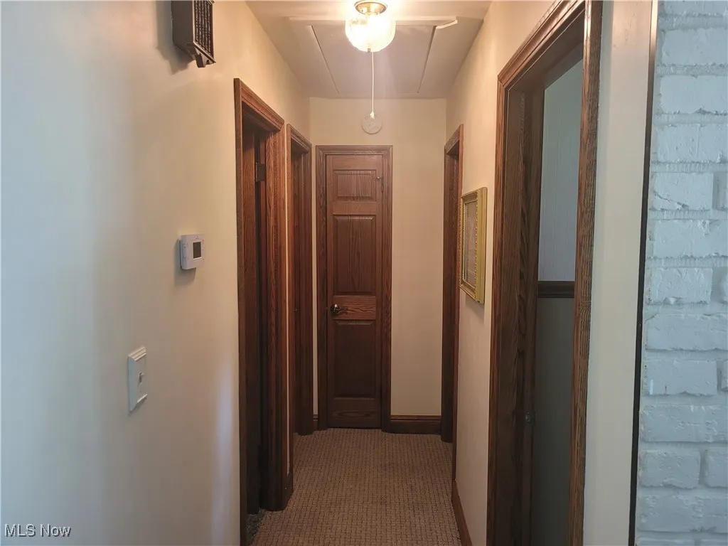 Hallway featuring attic access and baseboards