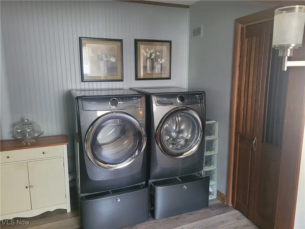 Washroom featuring dark wood-style flooring, separate washer and dryer, and cabinet space