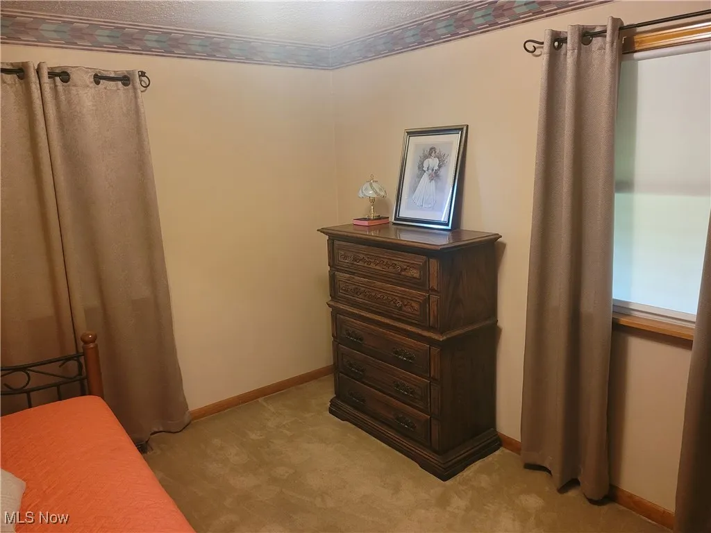 Bedroom with a textured ceiling, crown molding, and light carpet