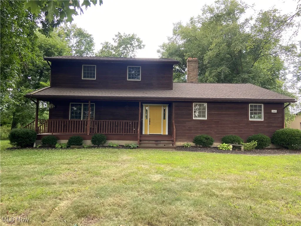 View of front of property featuring a porch, a chimney, a front yard, and roof with shingles