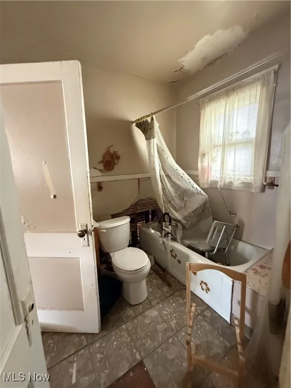 Bathroom with shower / bath combo with shower curtain and toilet