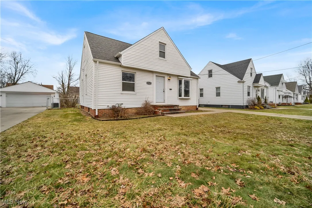 View of front of house with an outdoor structure, a front lawn, and a detached garage