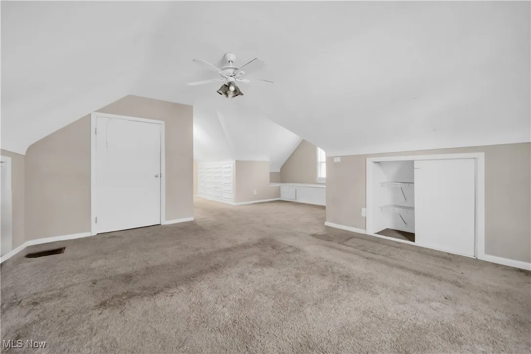 Bonus room featuring baseboards, carpet floors, lofted ceiling, and a ceiling fan