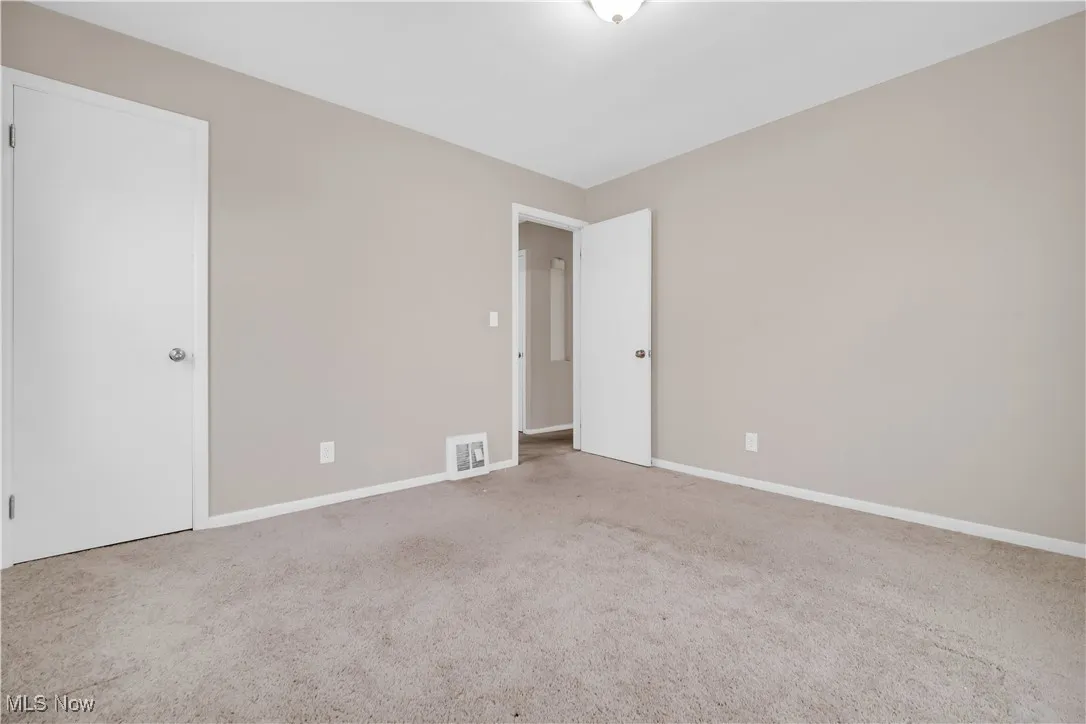 Carpeted empty room with visible vents and baseboards