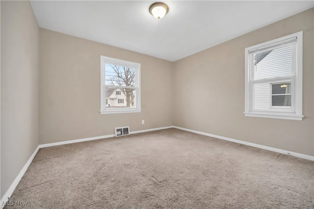 Carpeted spare room with visible vents and baseboards