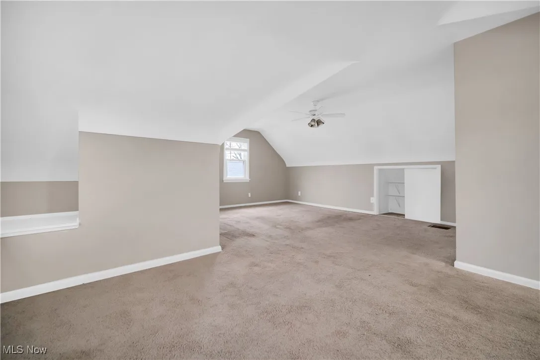 Bonus room featuring a ceiling fan, carpet, baseboards, visible vents, and vaulted ceiling