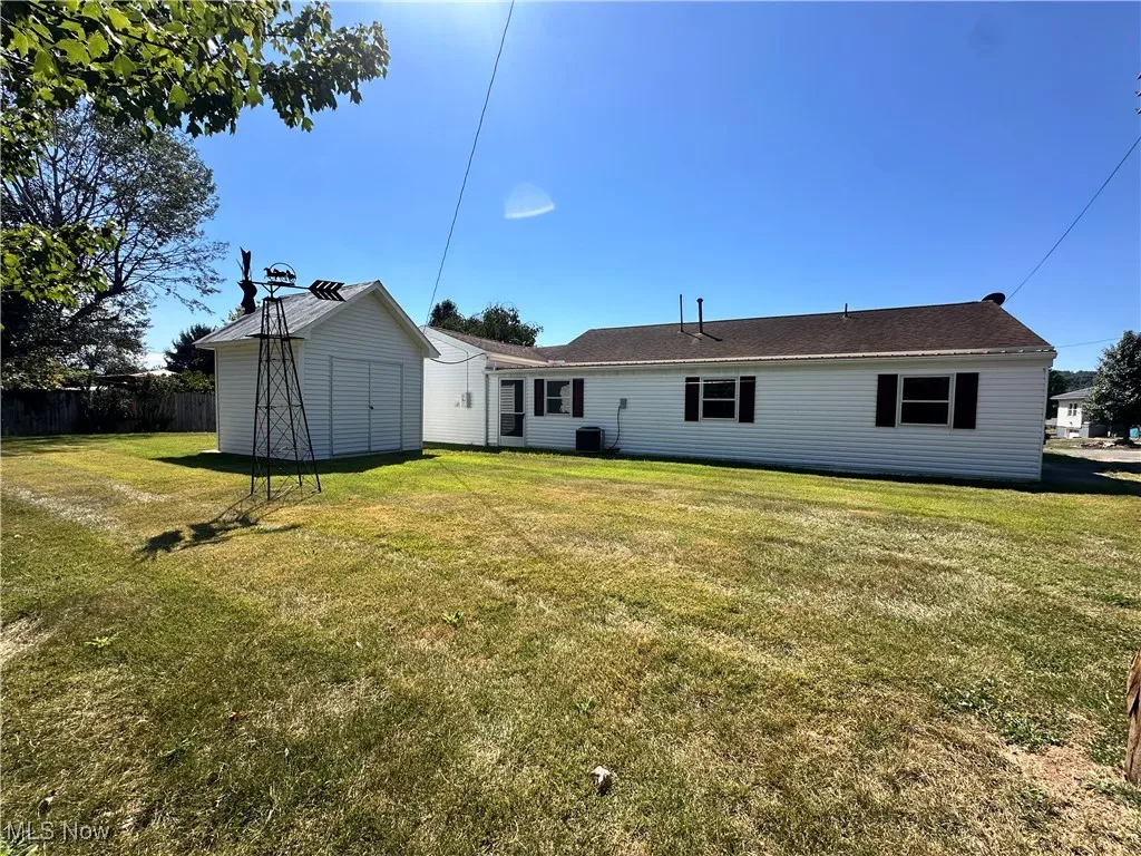 Back view of home featuring shed