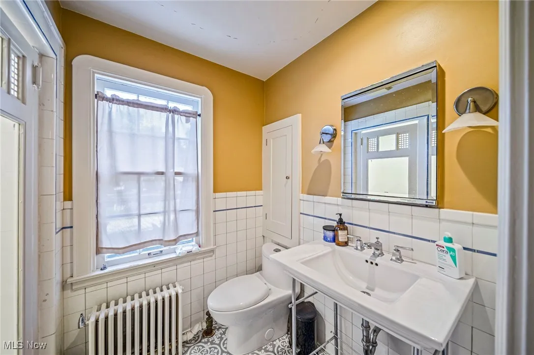 Bathroom featuring radiator, tile walls, wainscoting, and tile patterned flooring
