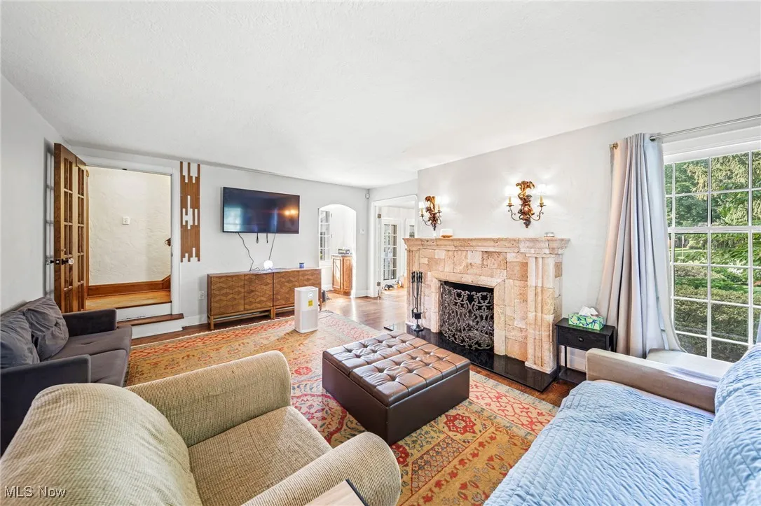 Living room with arched walkways, a fireplace, and wood finished floors