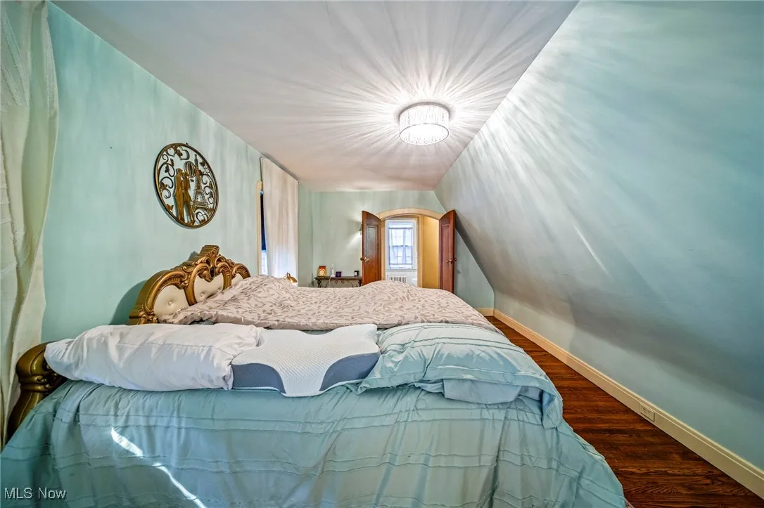 Bedroom featuring wood finished floors and vaulted ceiling