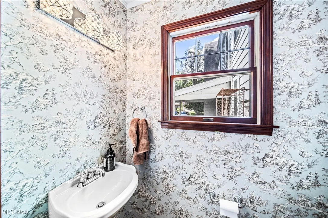 Bathroom with wallpapered walls and crown molding