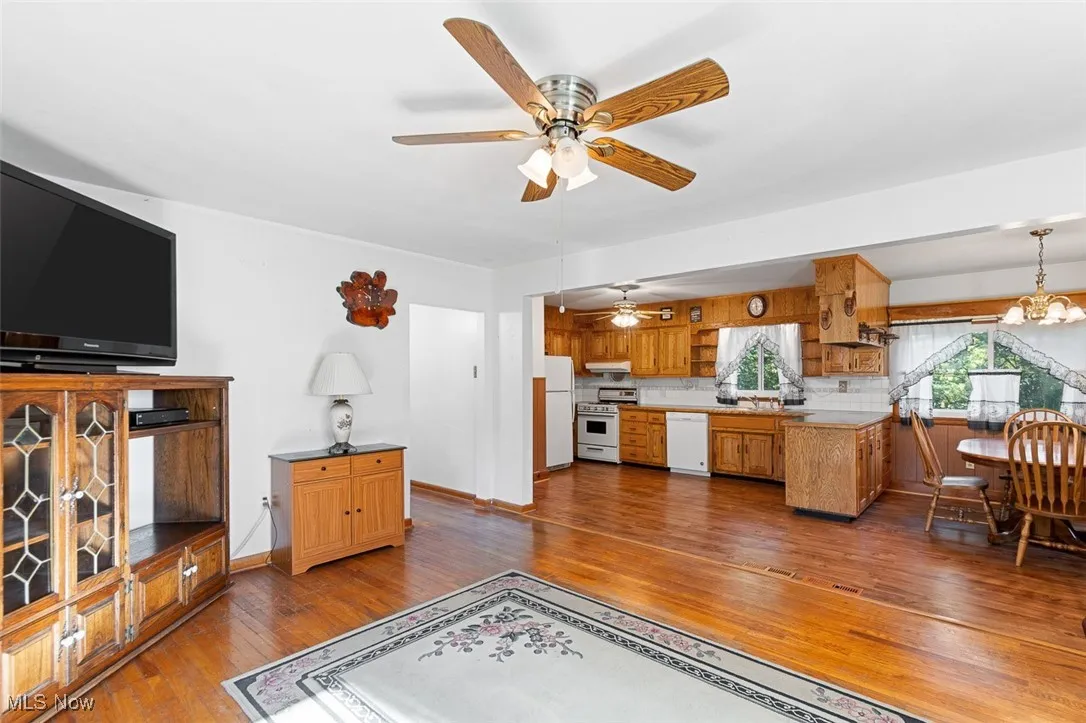 Living area with dark wood-style floors, a chandelier, and a ceiling fan