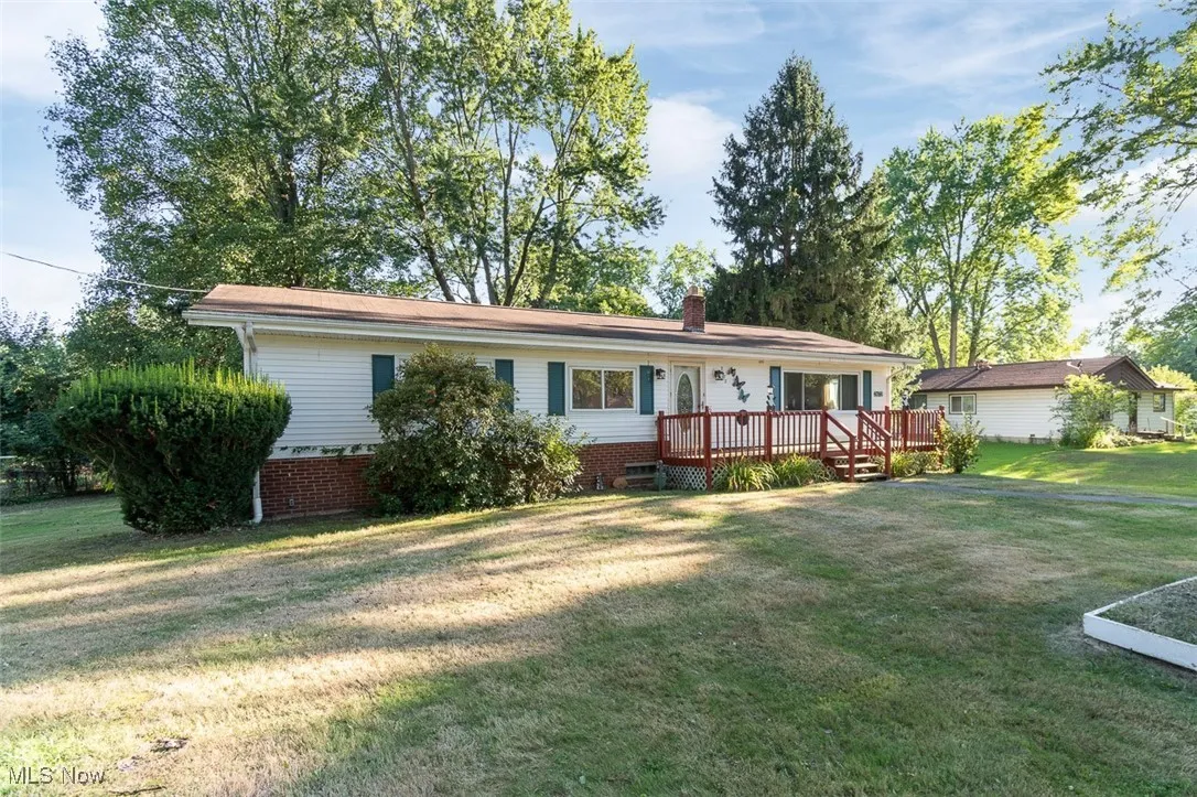 Single story home featuring a front lawn, a wooden deck, and a chimney