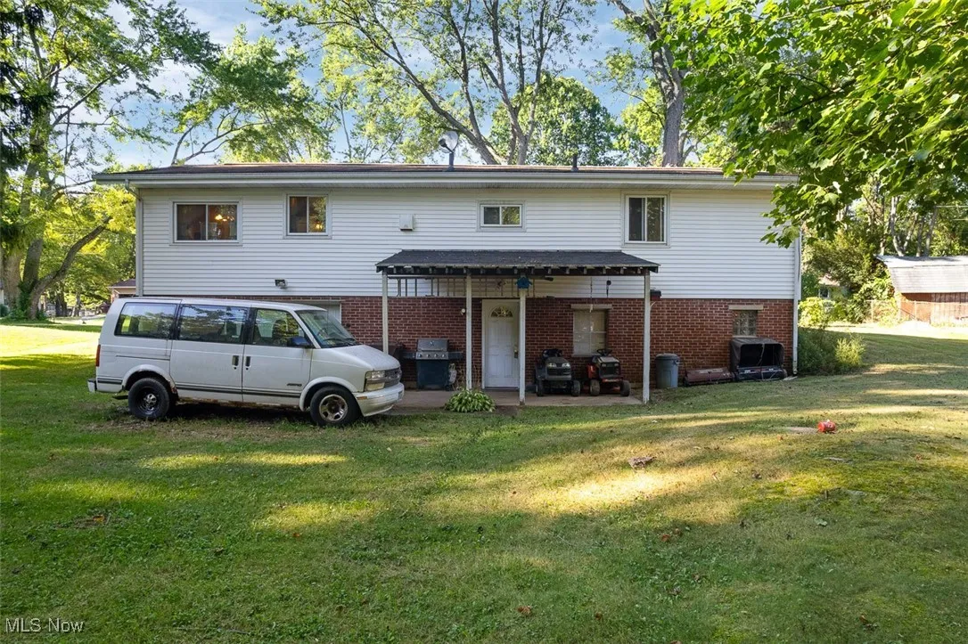 Rear view of property with brick siding, a yard, and a patio area