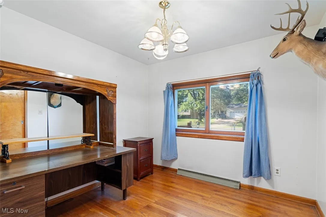 Bedroom featuring light wood-style floors, a baseboard heating unit, and a chandelier