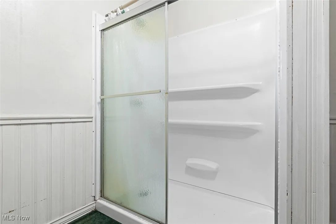 Bathroom featuring a stall shower and wainscoting