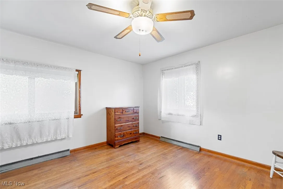 Bedroom featuring light wood-style floors, baseboard heating, a baseboard radiator, and a ceiling fan