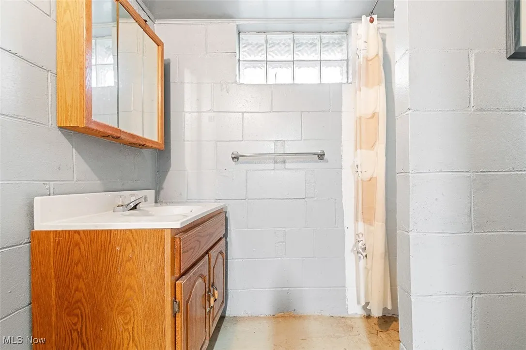Full bath with vanity, curtained shower, and concrete flooring