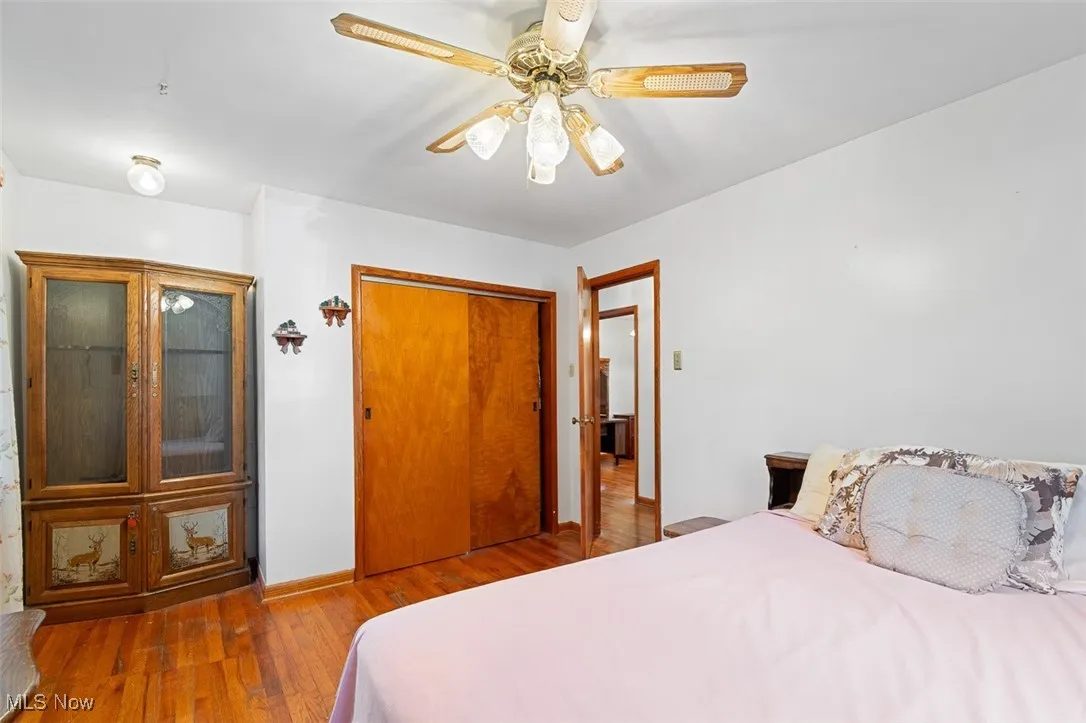 Bedroom with wood finished floors, ceiling fan, and a closet