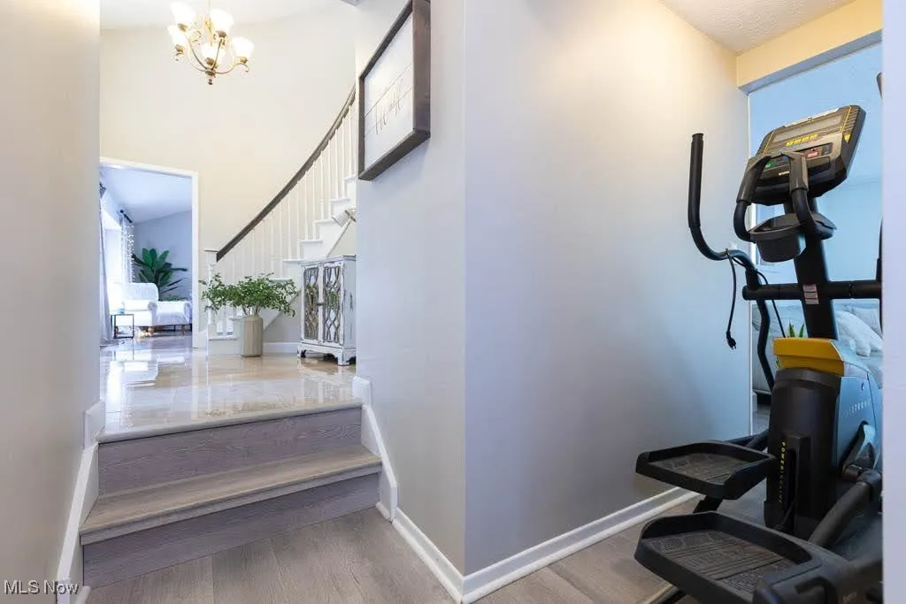 Staircase featuring wood finished floors, a chandelier, and a high ceiling