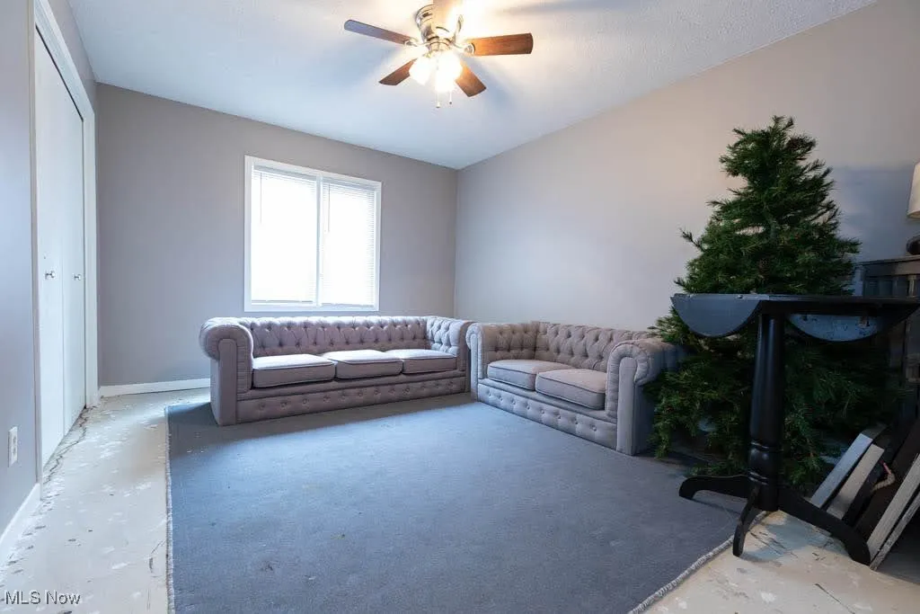 Living room featuring ceiling fan and baseboards