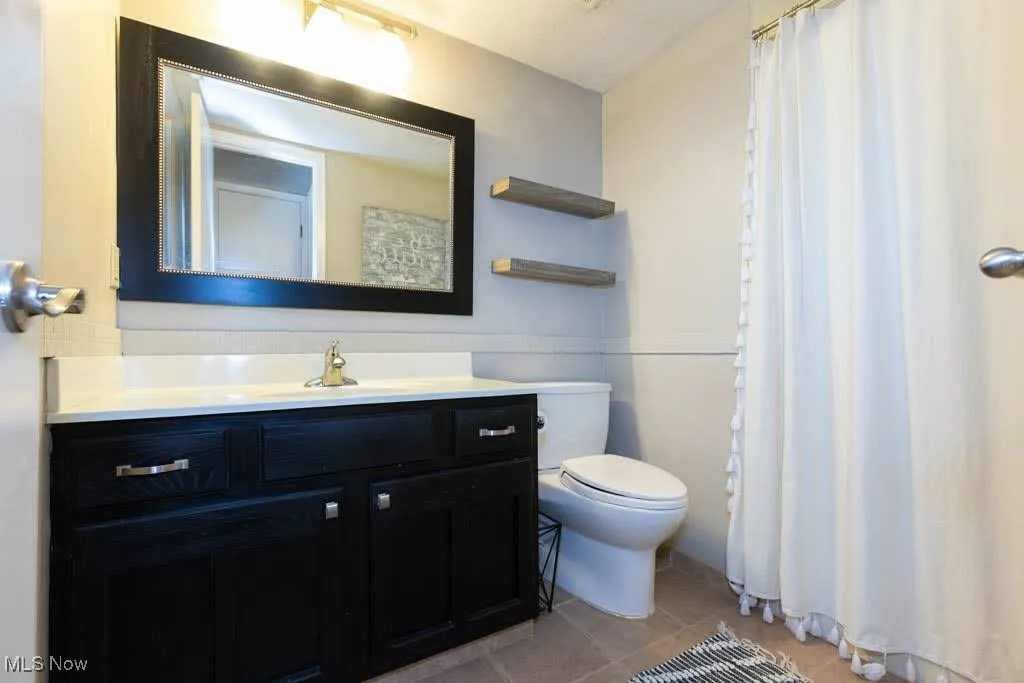 Bathroom with vanity, light tile patterned floors, and curtained shower