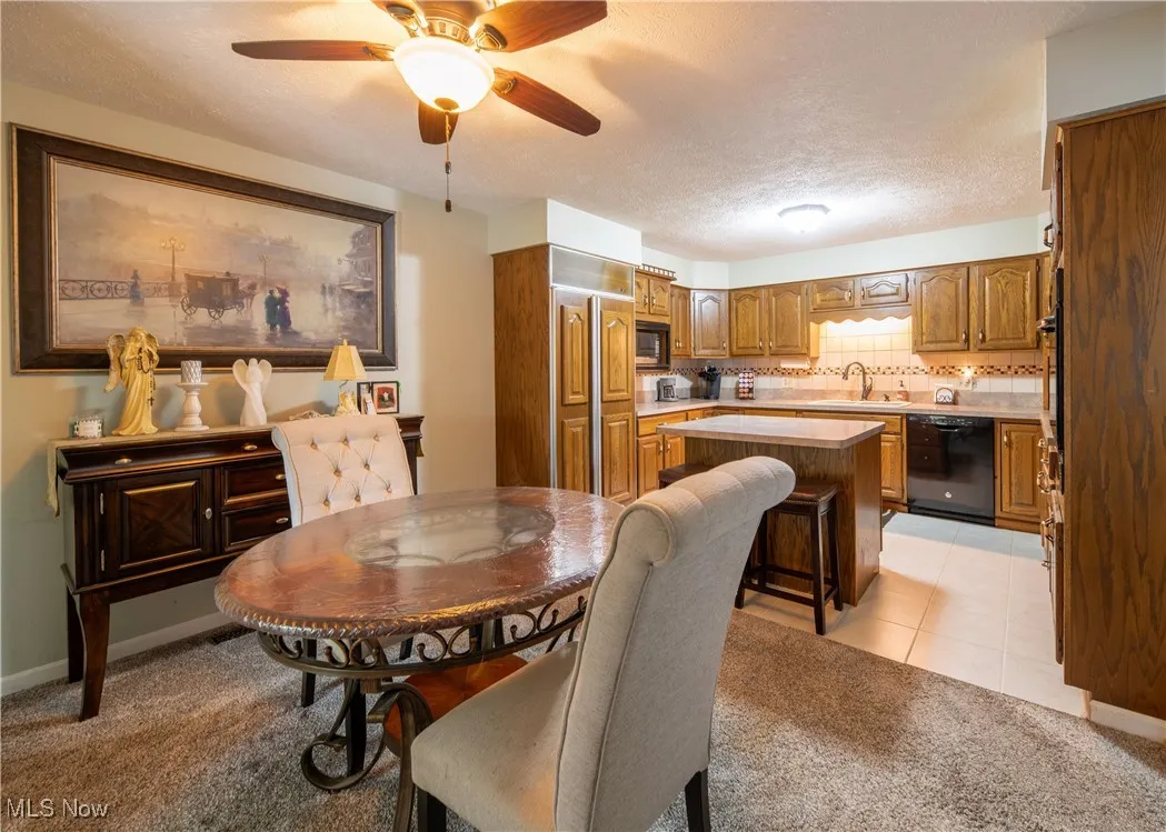 Dining area featuring a textured ceiling, light carpet, ceiling fan, and light tile patterned flooring