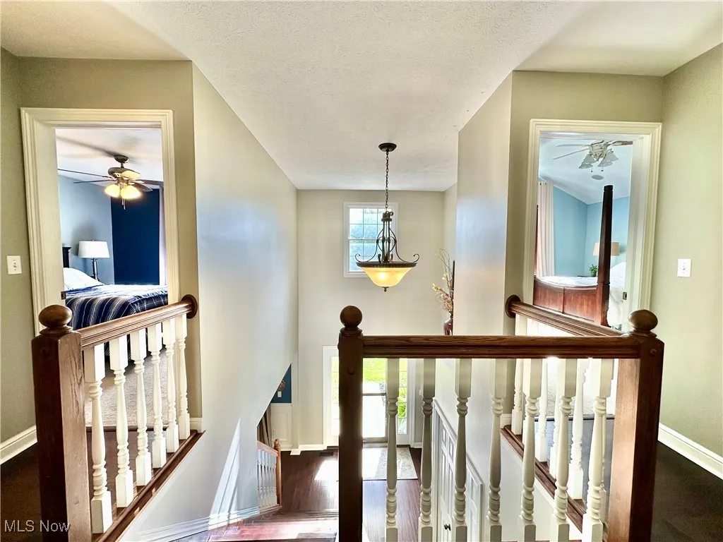 Stairway featuring wood finished floors, a ceiling fan, and a textured ceiling