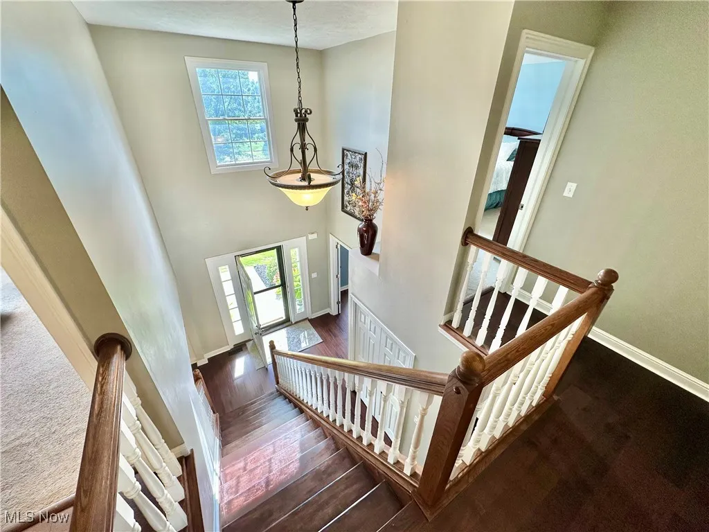 Staircase with a high ceiling, plenty of natural light, and wood finished floors