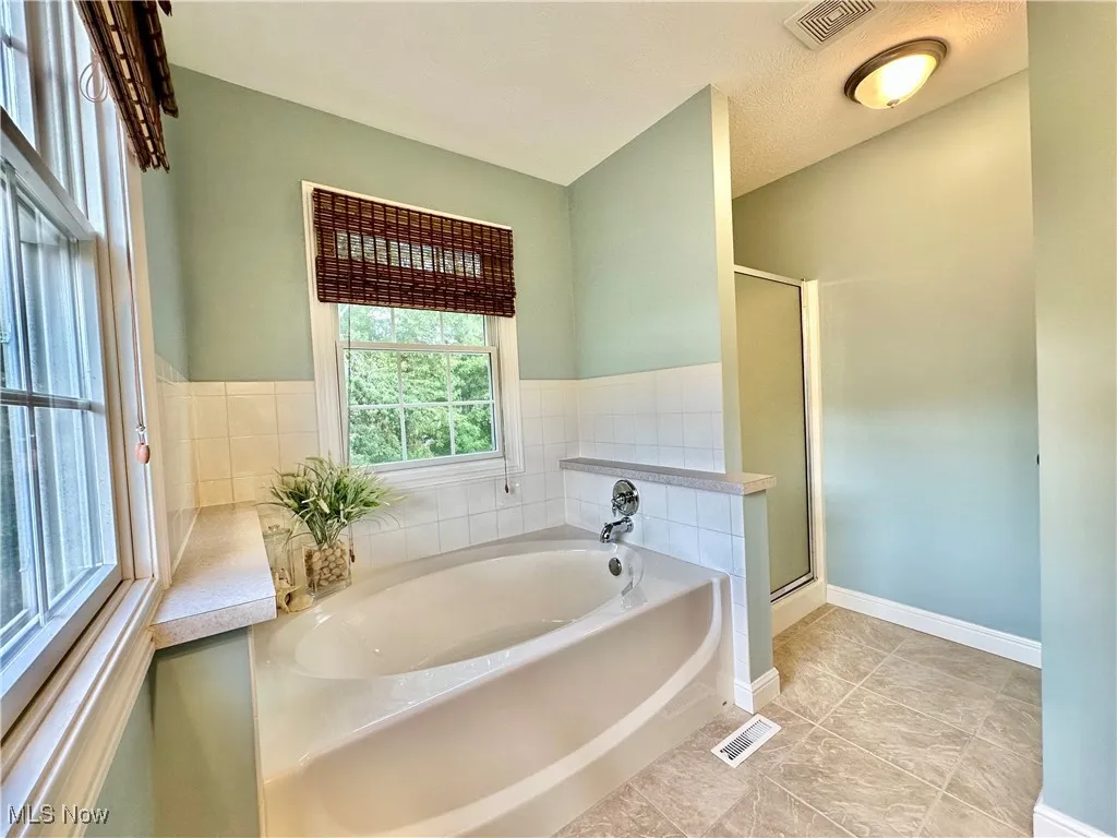 Full bathroom with a garden tub, a stall shower, and light tile patterned floors