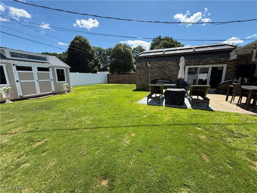 Fenced backyard with a storage unit and a patio area
