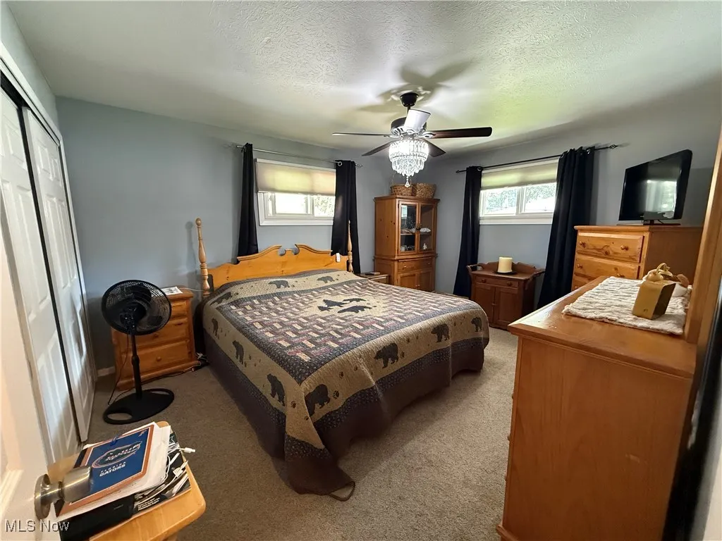 Carpeted bedroom featuring a closet, a textured ceiling, and a ceiling fan