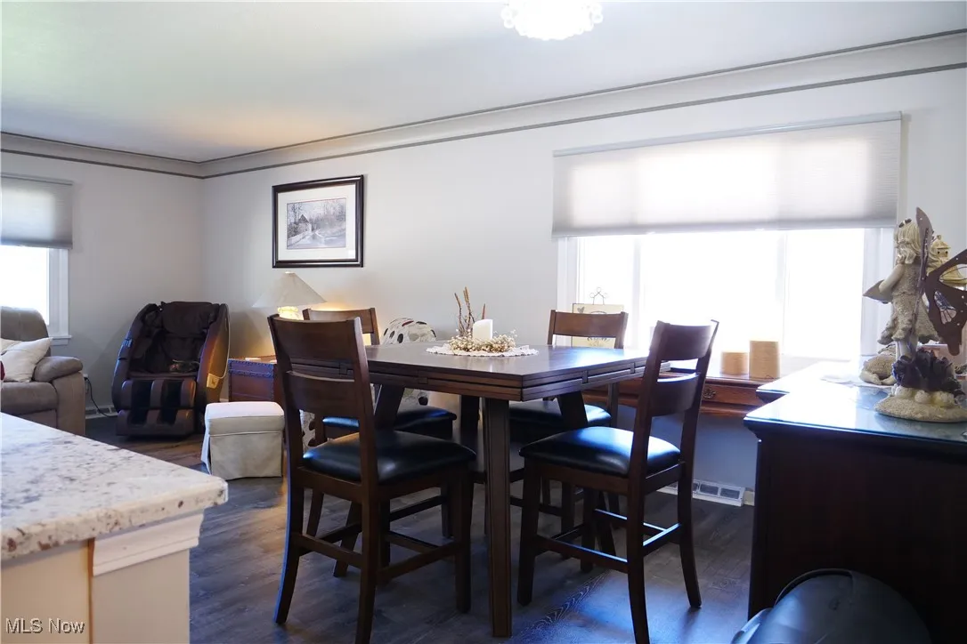 Dining area with dark wood-type flooring and crown molding