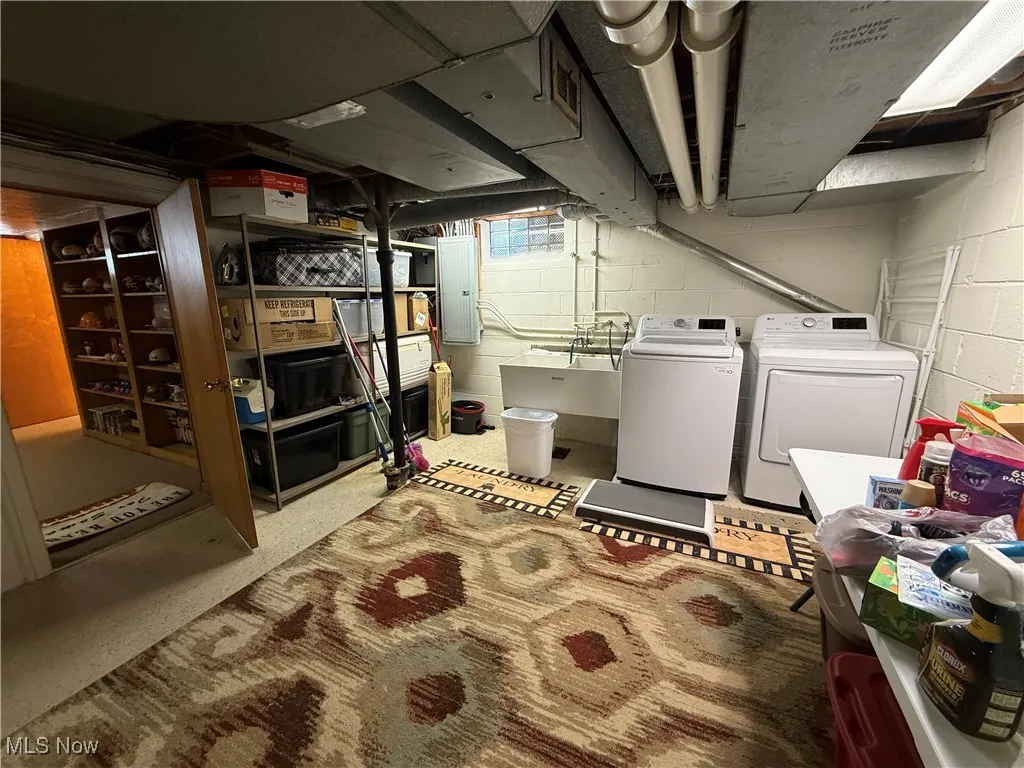 Basement featuring electric panel and washer and clothes dryer