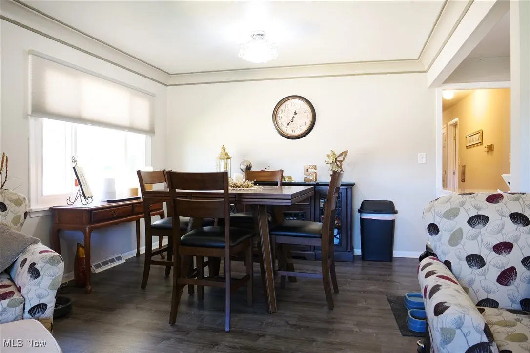 Dining area featuring crown molding and dark wood-type flooring