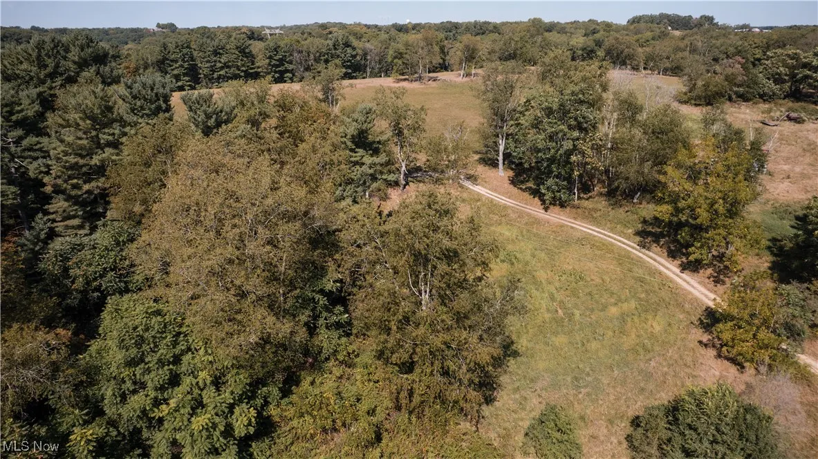 Aerial view of property and surrounding area with a heavily wooded area