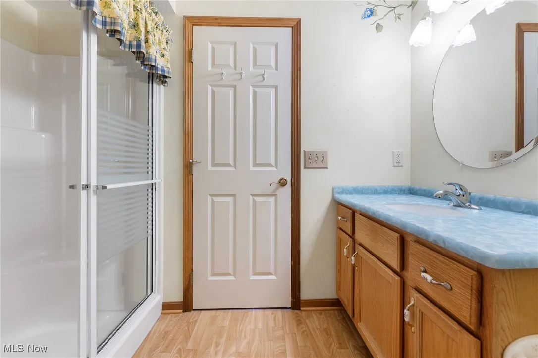Bathroom with a shower stall, vanity, and light wood-style floors