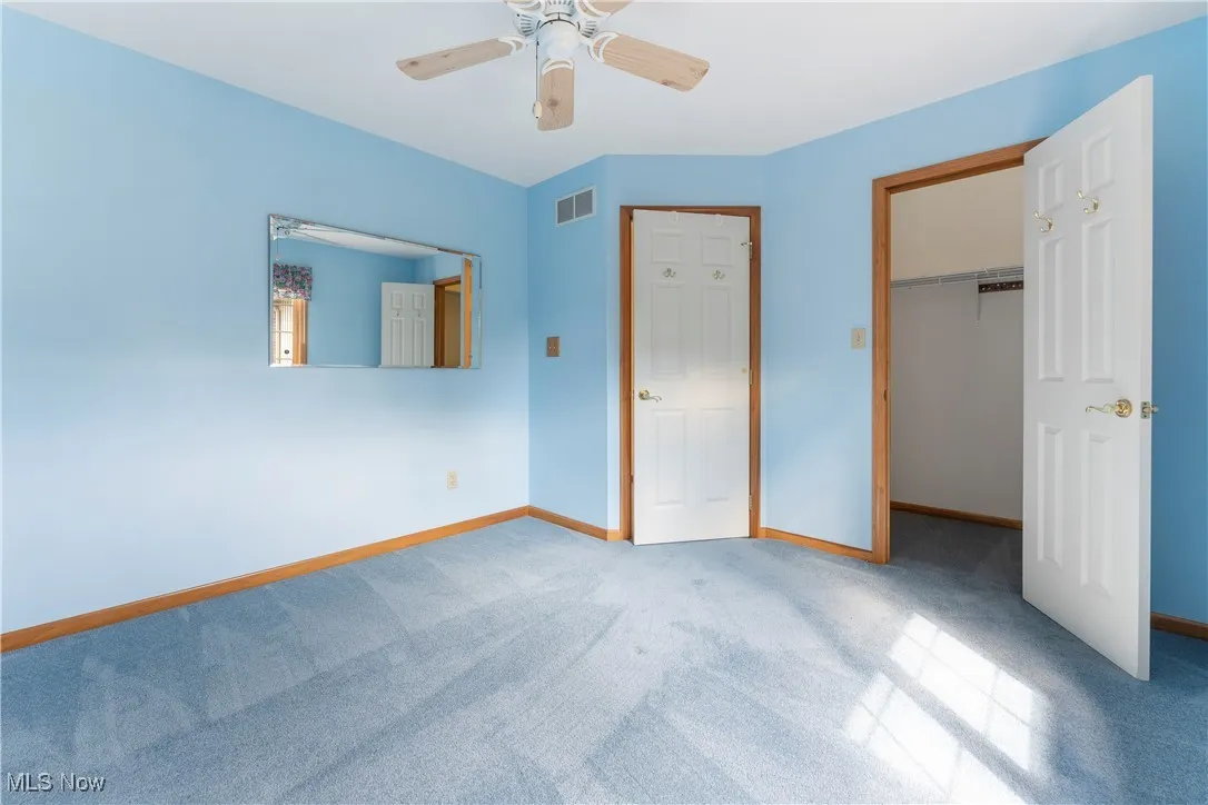 Unfurnished bedroom with carpet flooring, a walk in closet, and ceiling fan
